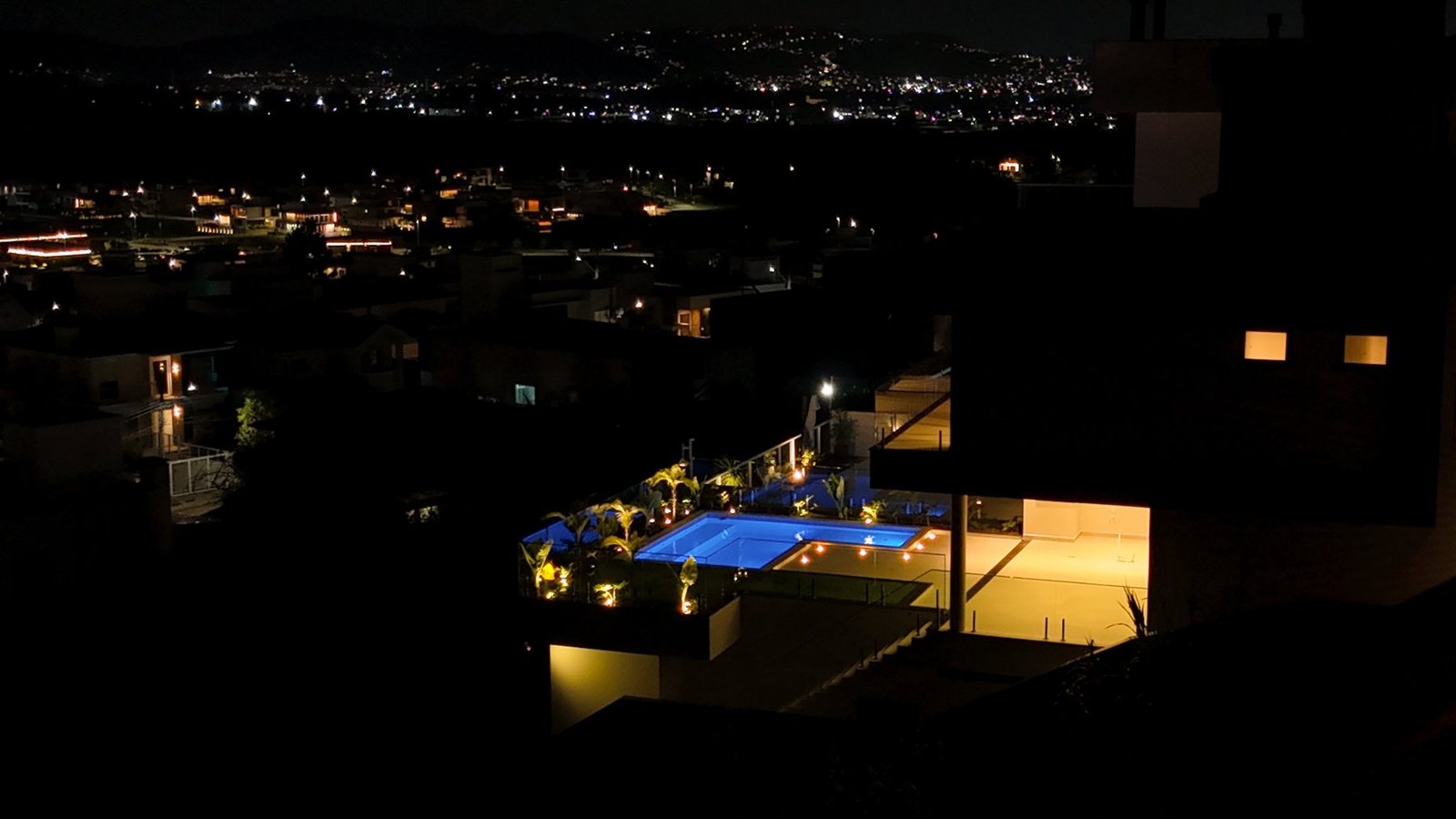 Vista aérea noturna da Casa Van Gogh com piscina iluminada